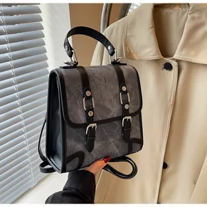 Detail of grey canvas backpack featuring black leather trim and silver metal buckles