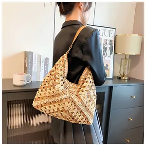 Détail du tissage au crochet ajouré et de la bandoulière en cuir du sac hobo en paille