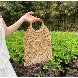 Detalle del tejido de macramé de un bolso de playa beige con asas redondas de madera