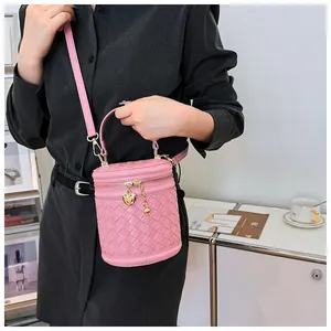 Détail du sac seau rose en cuir tressé avec pendentif coeur et fermeture éclair dorée