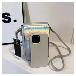 Mini silver holographic crossbody bag size comparison with a mobile smartphone