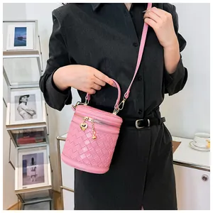 Détail du sac seau rose tressé avec pendentif cœur et bandoulière en cuir réglable