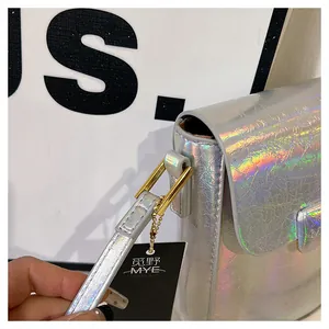 Detail of holographic silver mini crossbody bag featuring metallic texture and golden hardware