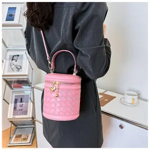 Détail du sac seau tressé rose avec breloque cœur et bandoulière amovible élégante