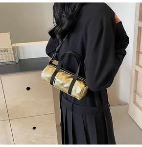Detail view of metallic gold cylindrical pillow bag with black woven handles and strap