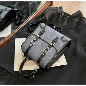 Detail of vintage grey denim satchel featuring silver buckles and black leather trim