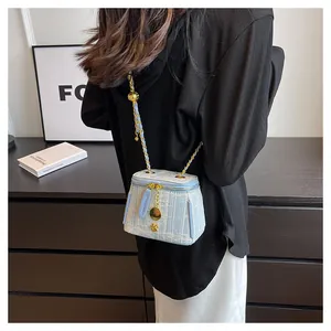 Detail of light blue tweed mini bucket bag with gold chain and adjustable ball