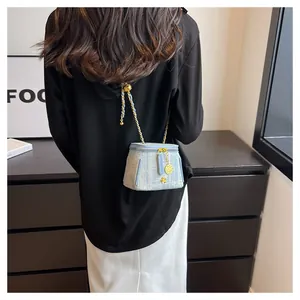 Detailed view of light blue tweed bucket bag with gold chain strap worn by a model