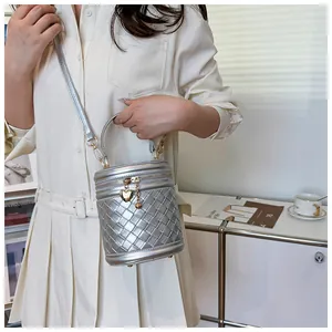 Détail du sac seau métallisé argenté avec pendentif en cœur et texture tressée