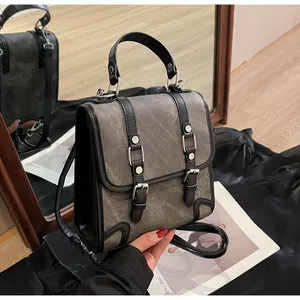 Detail of gray canvas backpack with black leather trim and silver metal buckle accents