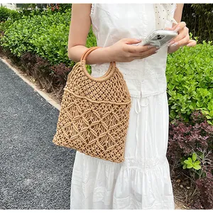 Detalle de bolso de paja tejido a mano con diseño calado y asa redonda de madera