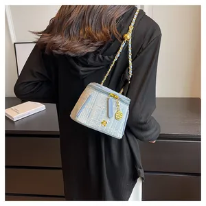 Detail of light blue tweed bucket bag with gold chain strap and camellia charm