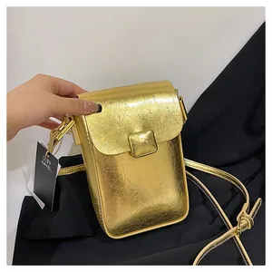 Detail of a mini gold crossbody bag with metallic crinkle texture and square buckle