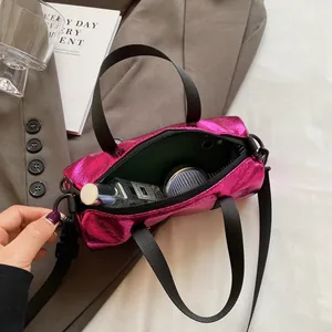 Metallic rose pink pillow barrel bag with black nylon handles and crossbody strap