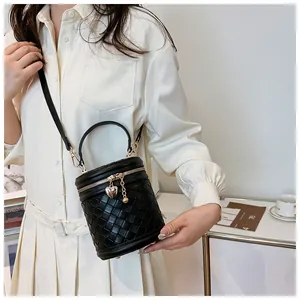 Détail d'un sac seau tressé noir montrant la texture du cuir et le charme en cœur