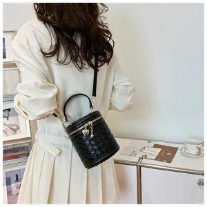 Vue détaillée du sac seau cylindrique noir tressé avec breloque coeur dorée et fermeture