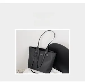 Detail view of the black waterproof nylon tote bag with a minimalist logo plaque