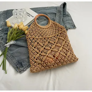 Detalle del bolso de macramé hecho a mano con motivos florales y asas redondas de madera