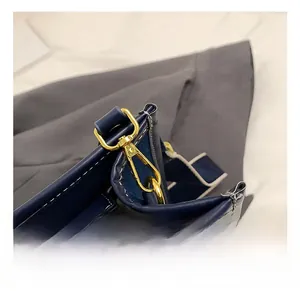 Detailed close-up of navy blue leather patchwork with golden metal hardware and zipper