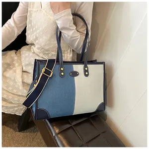 Detail of blue and white tote bag with adjustable woven strap and leather handles