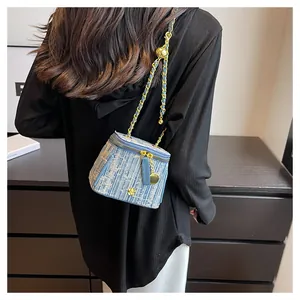 Light blue tweed bucket bag with gold chain strap shown from a back-view perspective