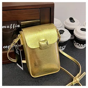 Detail of metallic gold textured phone bag with square buckle and brand tag on wood