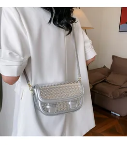 Detailed view of silver woven saddle bag showing textured metallic finish and gold hardware