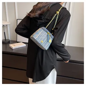 Detail of light blue tweed crossbody bag with golden chain and adjustable metal ball