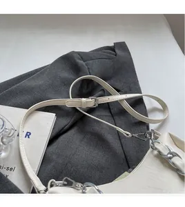 Detail of adjustable white strap and silver chain on a stylish square shoulder bag