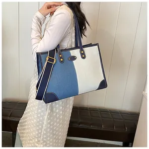 Blue and white canvas tote bag with leather trim and wide shoulder strap shown on model