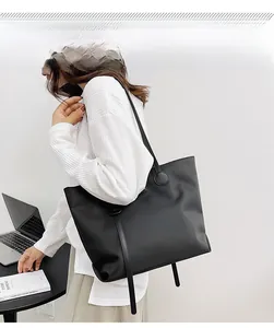 Black waterproof nylon tote bag next to a laptop showing large capacity for work