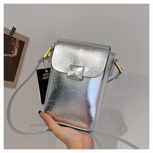 Detail of silver metallic mini crossbody phone bag with gold magnetic buckle and logo