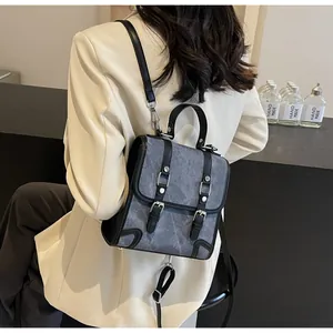 Detail of vintage grey canvas backpack with black leather trim worn on a beige blazer