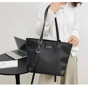 Waterproof black nylon tote bag shown on a table in a minimalist office setting