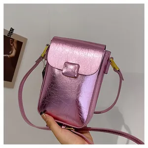 Detail of metallic pink mini crossbody phone bag with textured leather and gold hardware