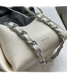 Detailed close-up of textured leather underarm bag with silver chain strap and brand logo