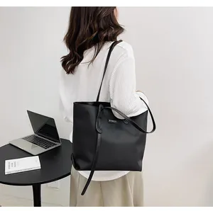 Close-up of waterproof nylon tote bag featuring a brand logo tag and slim shoulder straps