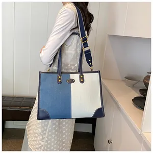 Model showing contrast denim tote bag with adjustable strap in a bright interior