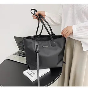 Detail of waterproof nylon tote bag with leather strap connectors and metal logo plaque