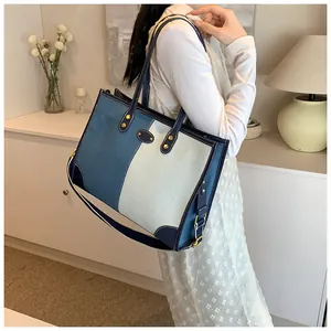 Detail of color-block denim tote bag showing wide shoulder strap and gold-tone metal clips