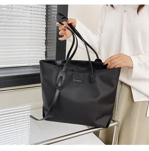 Detail of the waterproof nylon tote bag showing metallic logo plate and sturdy handles