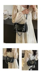 Detail of a black leather underarm bag with pleated texture and silver chain strap