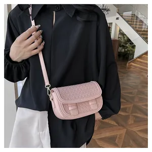 Detail of light pink woven crossbody saddle bag with adjustable leather strap and gold hardware