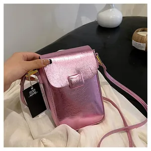 Close-up of pink metallic textured mini crossbody bag featuring a branded logo debossing