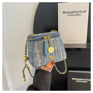 Detail of blue tweed vanity bag featuring a gold camellia charm and woven chain strap