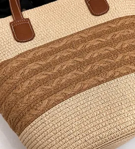 Detalle de bolso tote de paja tejida con motivos beige y asas de cuero marrón