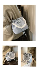 Detail of light blue drawstring bucket bag with frosted white bead handle and silver hardware