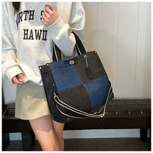 Détail d'un grand sac cabas en denim patchwork avec fermoir doré et bandoulière