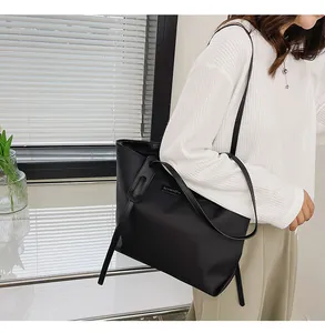 Detail of waterproof black nylon tote bag with polished logo and stylish shoulder strap