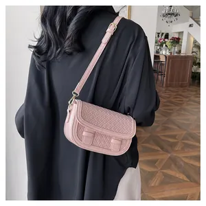Detail of pink woven saddle bag showing PU leather texture and gold hardware details